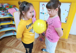 Dziewczyny tańczą trzymając balon brzuchami